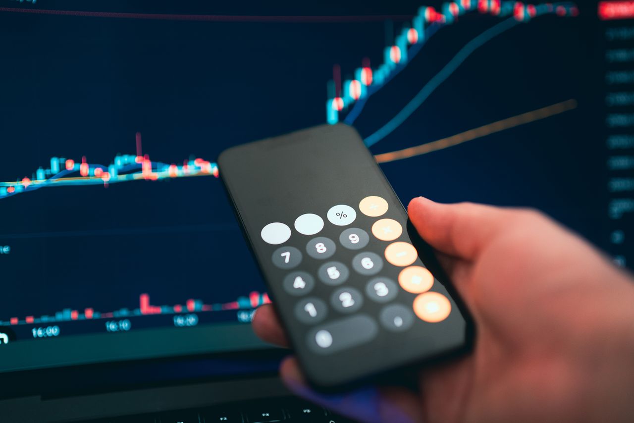 Services Close-up of a smartphone displaying a calculator with a financial chart in the background.